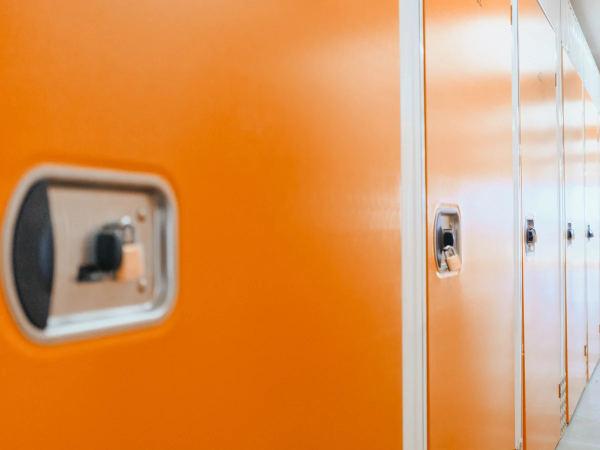 Reihe orangefarbener Boxtüren mit Schlossaufnahme in einem Gang der Anlage